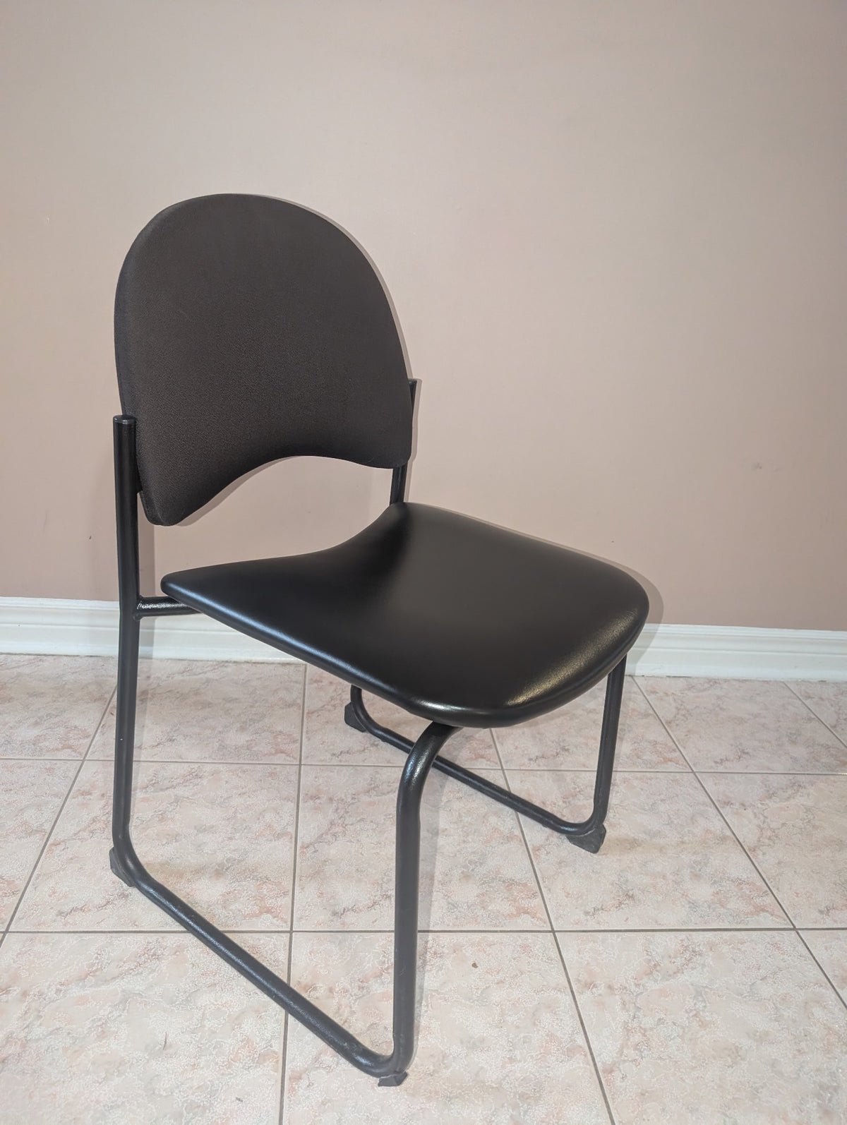 Black guest chair with fabric backrest and metal sled base, view 1