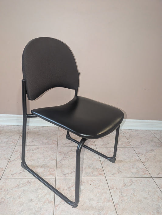 Black guest chair with fabric backrest and metal sled base, view 1