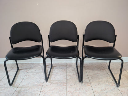 Black guest chair with fabric backrest and metal sled base, view 3