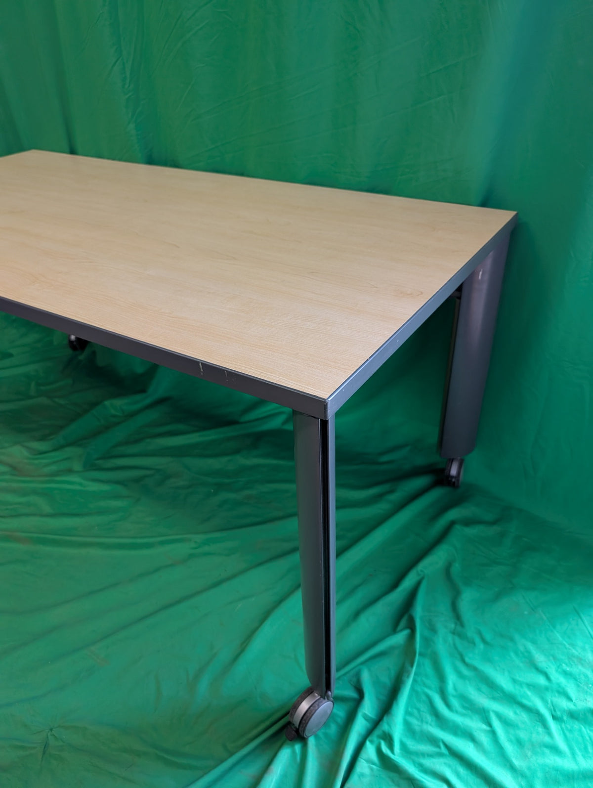 Woodgrain rectangular table with dark metal legs and casters, view 3