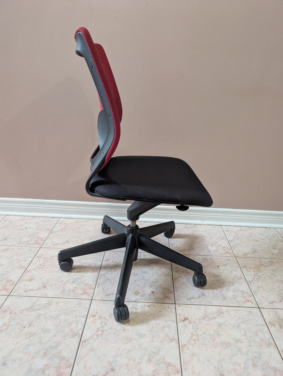 Armless office chair with contoured red backrest and black padded seat