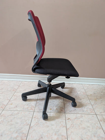Armless office chair with contoured red backrest and black padded seat