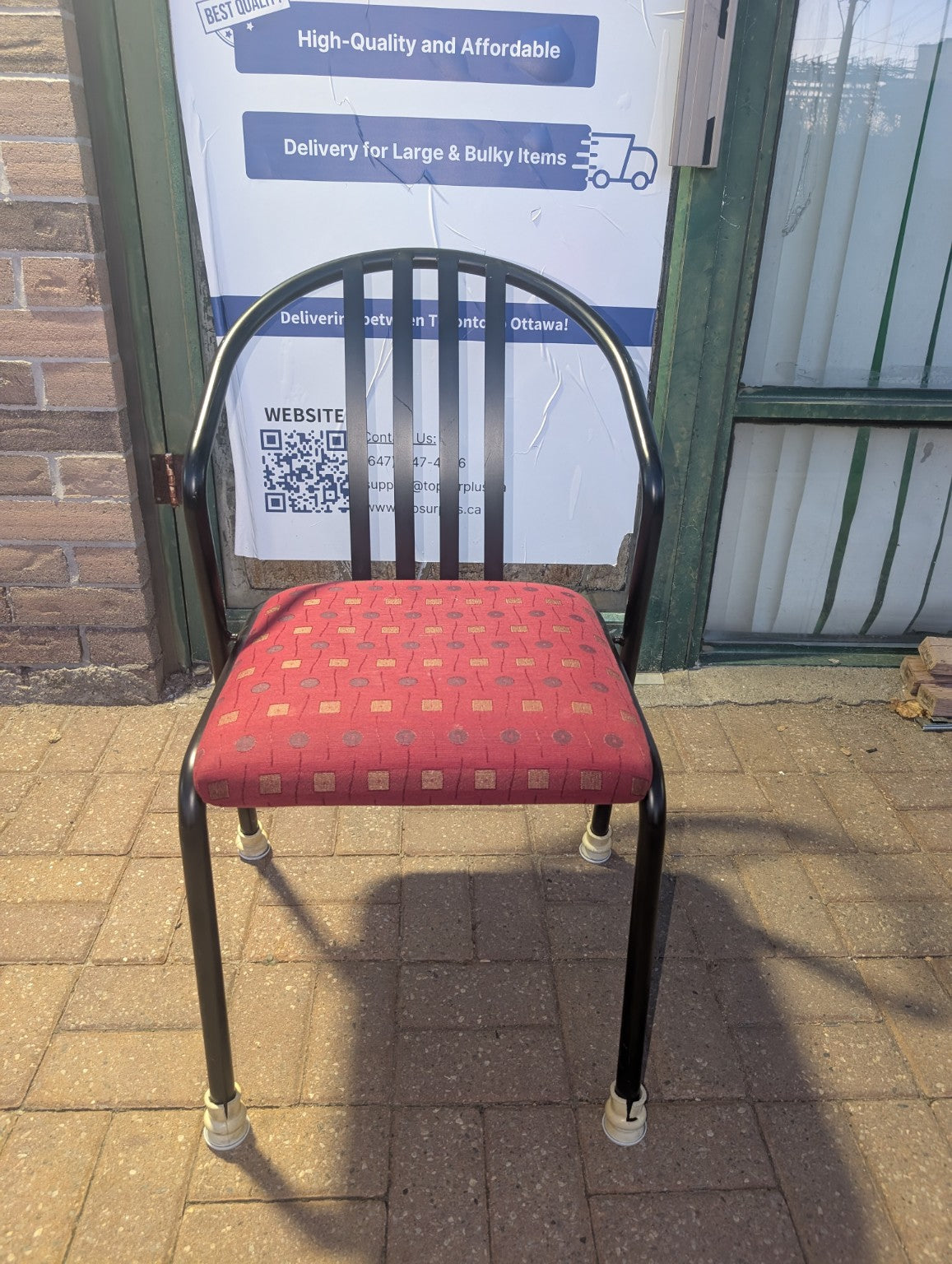 Red patterned upholstered stacking chair with black metal frame, front view